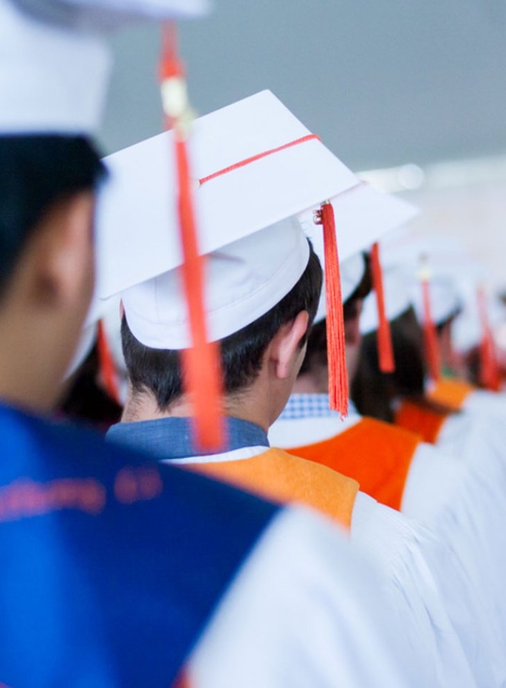 back view of a row of student wearing their graduation caps and tassels