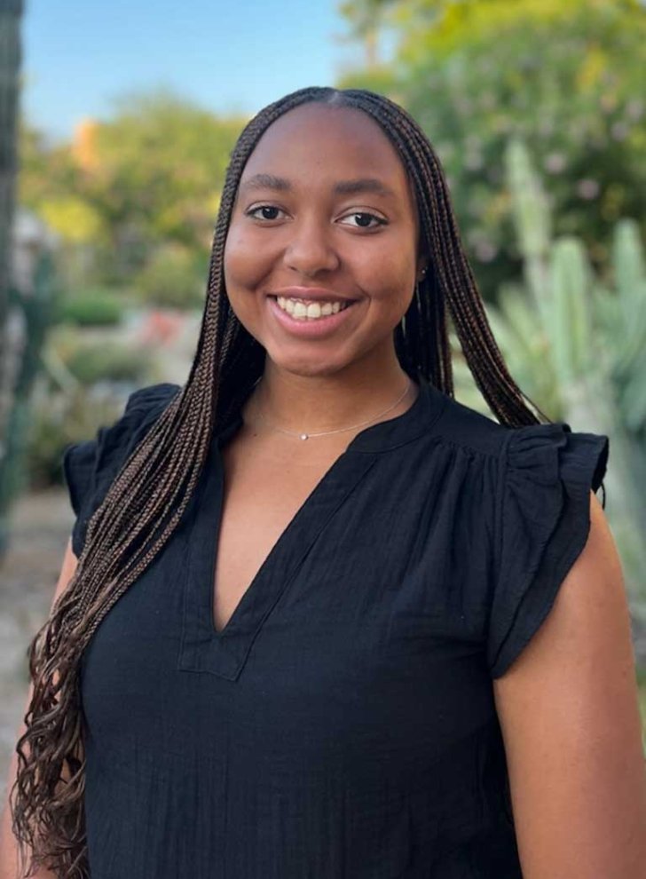 portrait of mia pickett wearing a black blouse, posing in front of a desert garden landscape