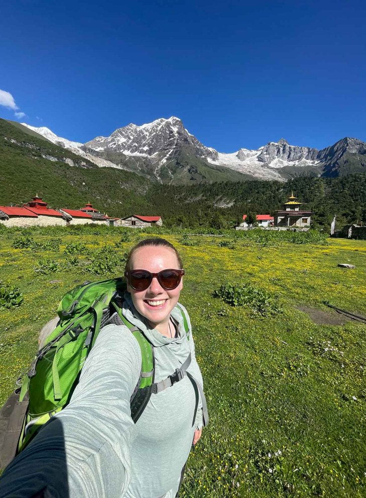 Madison Wilson takes a selfie in Nepal with mountains and temples behind her.