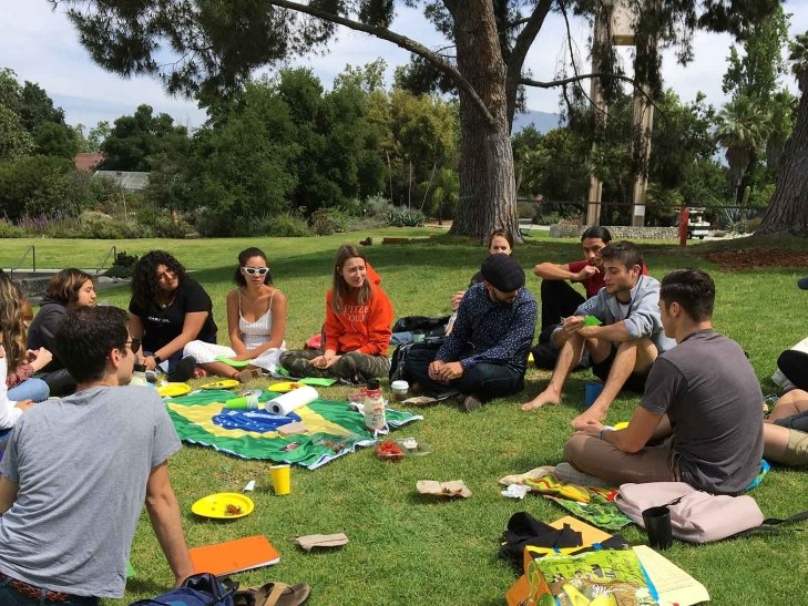 A Portuguese language class sits outside on the mounds. 