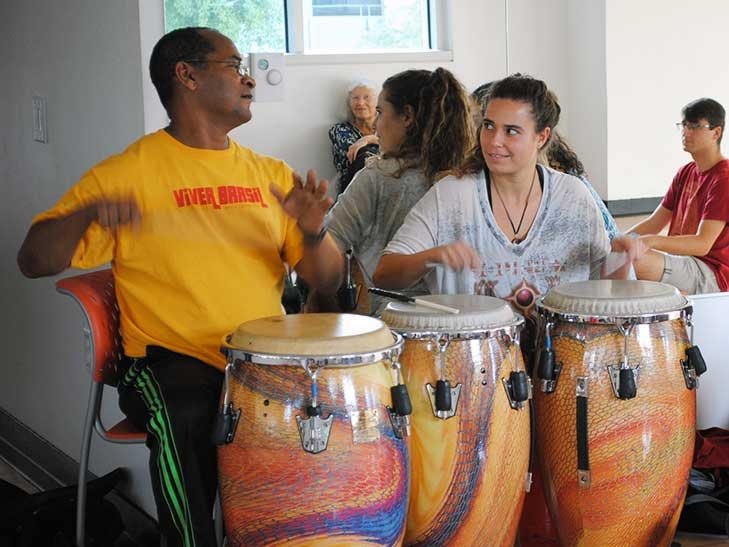a student plays the drums with a teacher during a workshop in Brazil