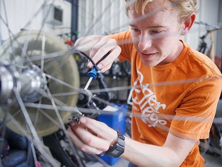 a student works on fixing a bike at the green bike program building