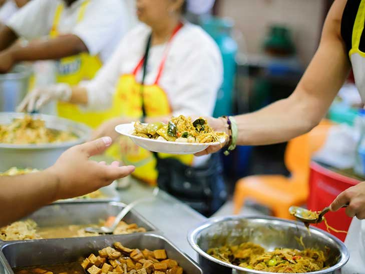 a person hands a plate of food to an outreached hand