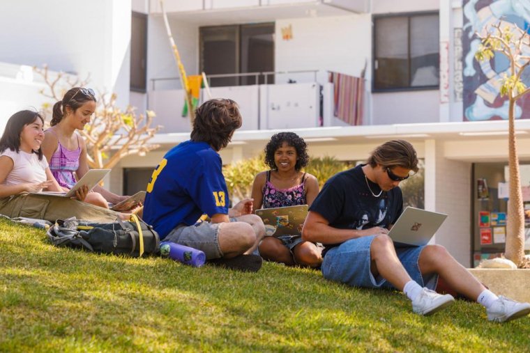 a group of students sits on the mounds in front of mead hall