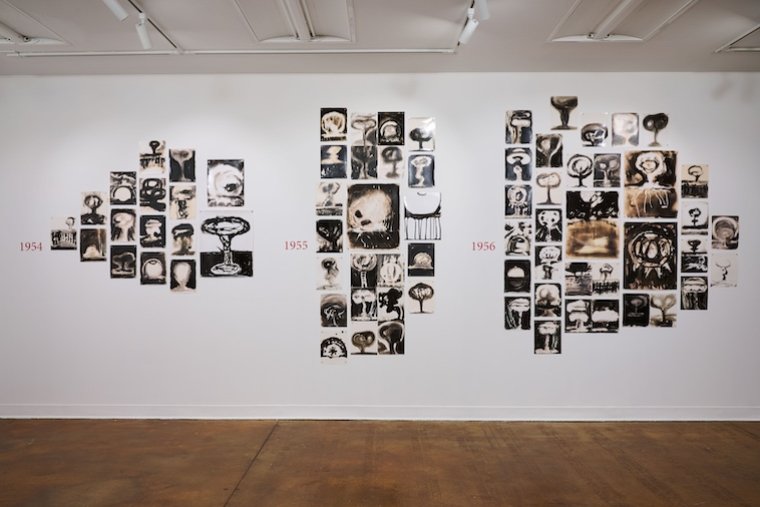 photographic drawings of mushroom clouds arranged on a wall