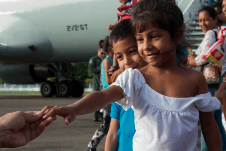 a girl reaches her hand out towards an outstretched hand