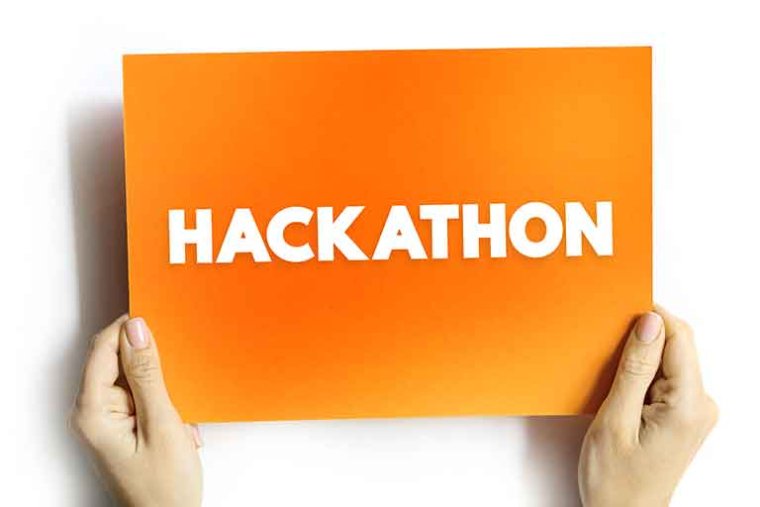 two hands hold up an orange sign with the words "hackathon" printed on it in white