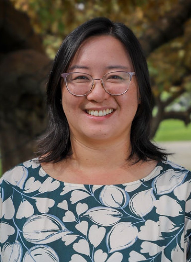 Closeup of Lisa Yin Han, who has shoulder-length straight black hair and wears glasses and a blue top with white floral print.