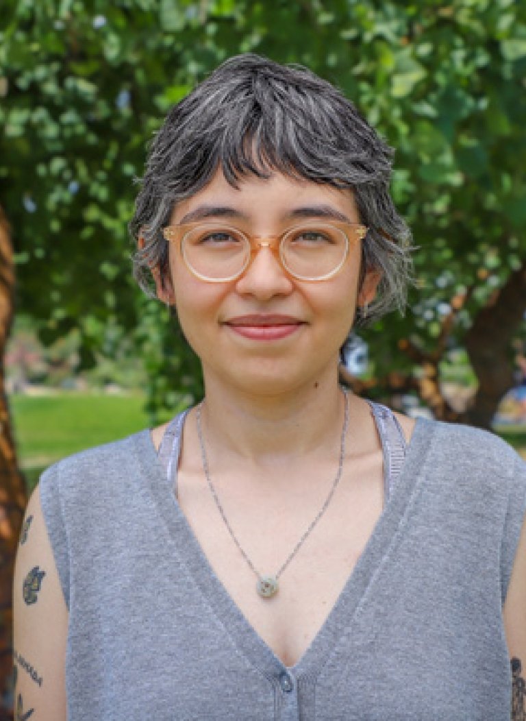 Debbie Duarte has cropped salt and pepper hair and wears glasses and a sleeveless gray top while standing outdoors.