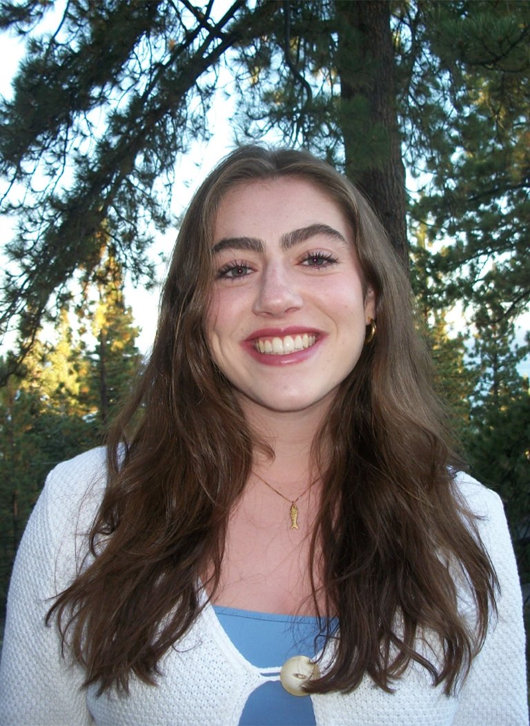 Woman wearing white cardigan with long brown hair.