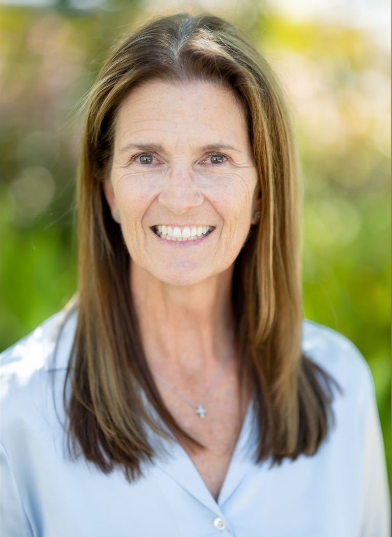 Woman in light blue blouse with short brown hair.