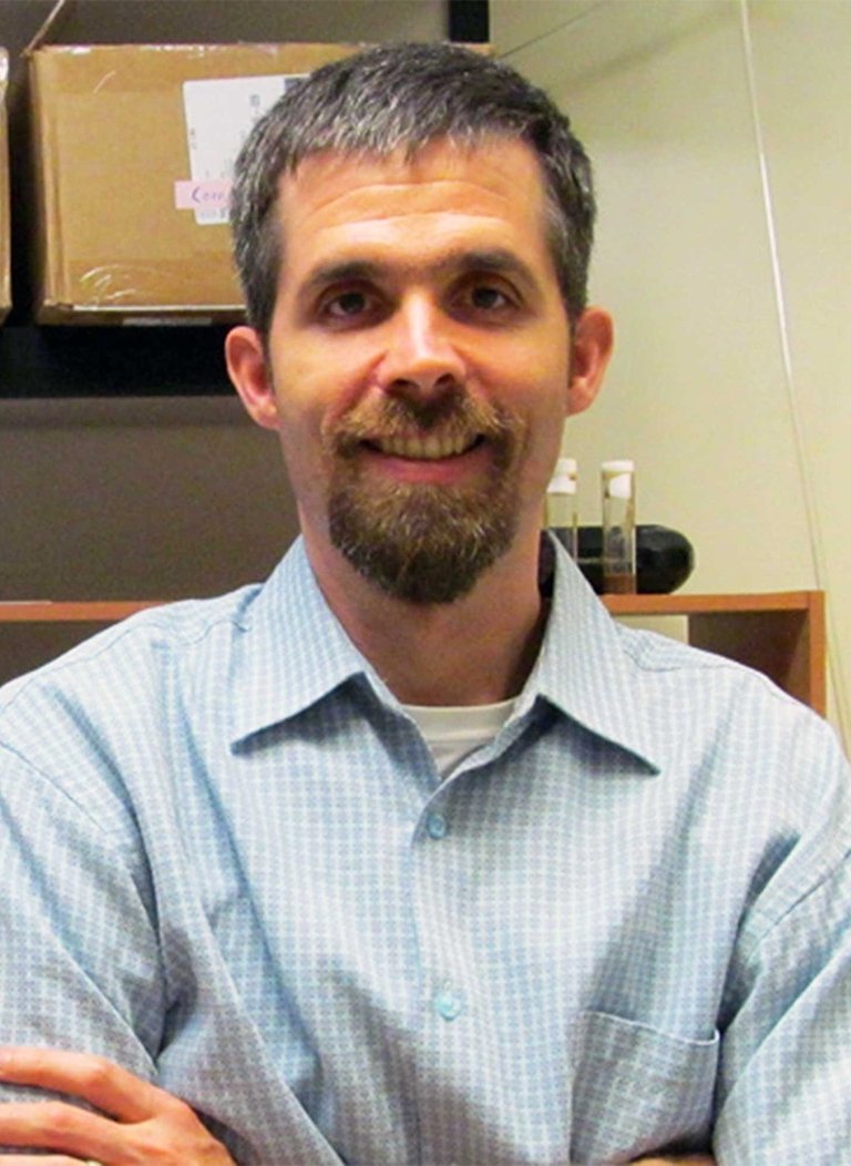 Man wearing light bluje button up with short grey hair.