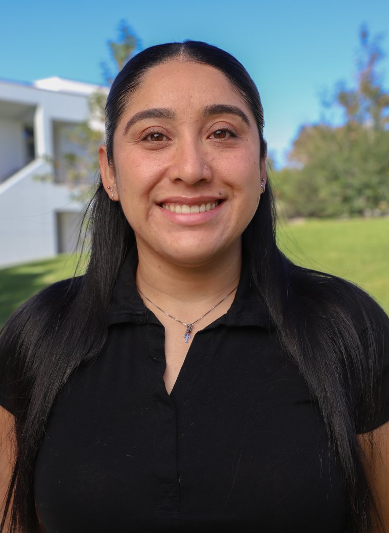 Woman with long black hair wearing black top with necklace.