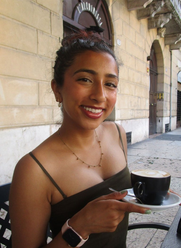 a girl with a cup of coffee sitting in front of a wall