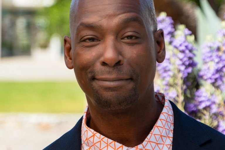 Portrait of Kenneth Butler in front of purple flowers. 