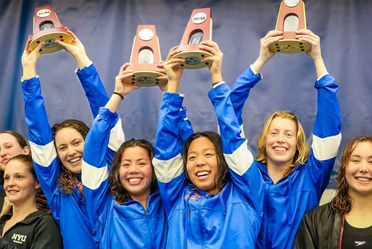 swim team poses with trophies