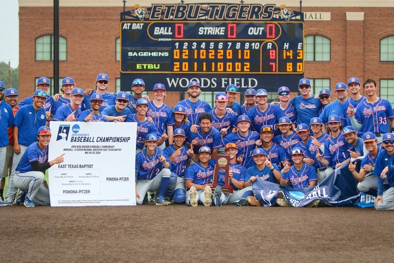 The Pomona-Pitzer men’s baseball team gather on the field in front of the score board with their NCAA trophy.