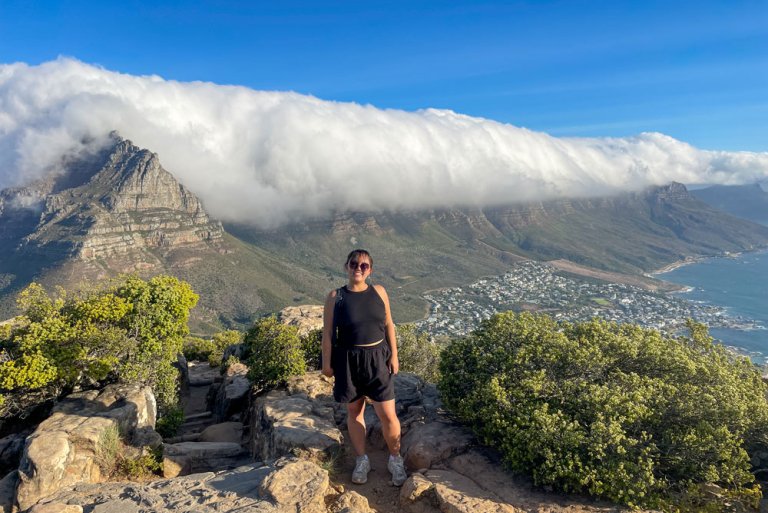 Natasha Yen stands on a hiking trail at Lion’s Head mountain with a backdrop of low-hanging clouds settling over the peaks.