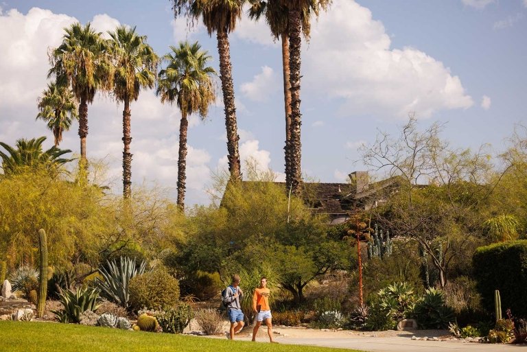 two student walk in front of the grove house  on a sunny day