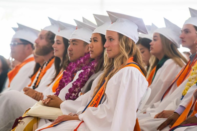 graduates sit in chair facing the stage in the pitzer commencement tent