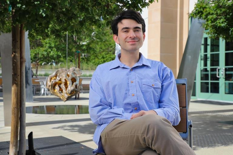 Lucas Oppenheimer sits on a chair in front of the Nucleus