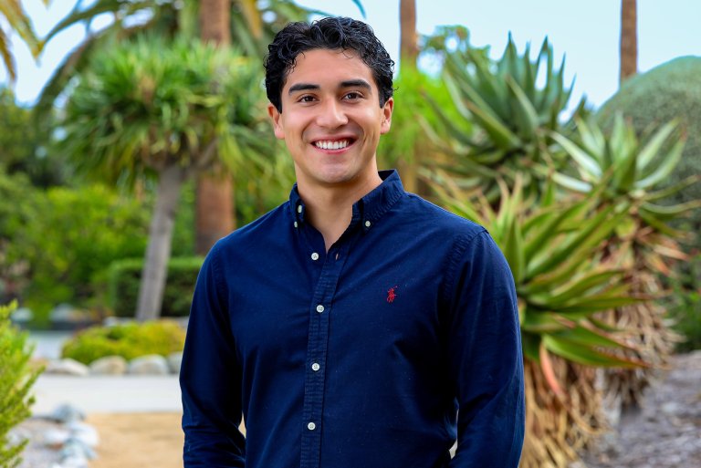 Sebastian maldonado standing in front of trees on the Pitzer campus