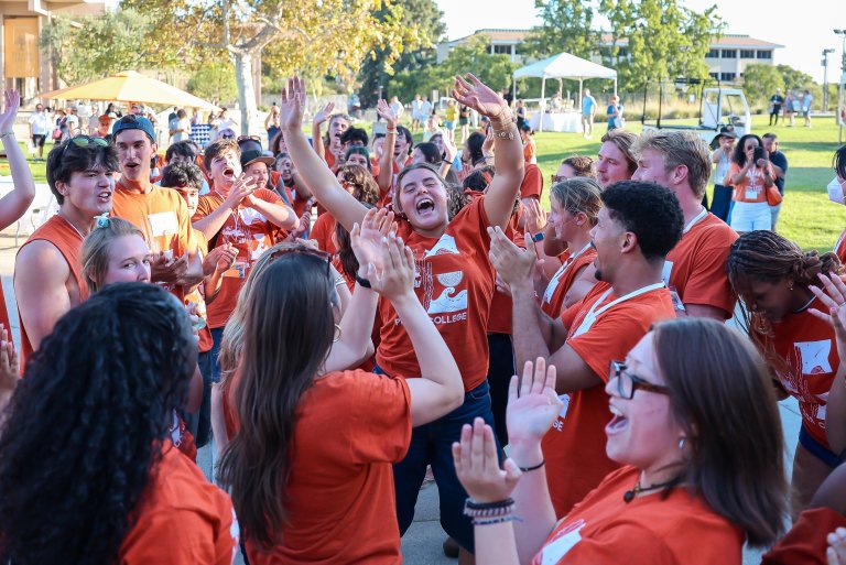 a group of students in orange shirts cheering