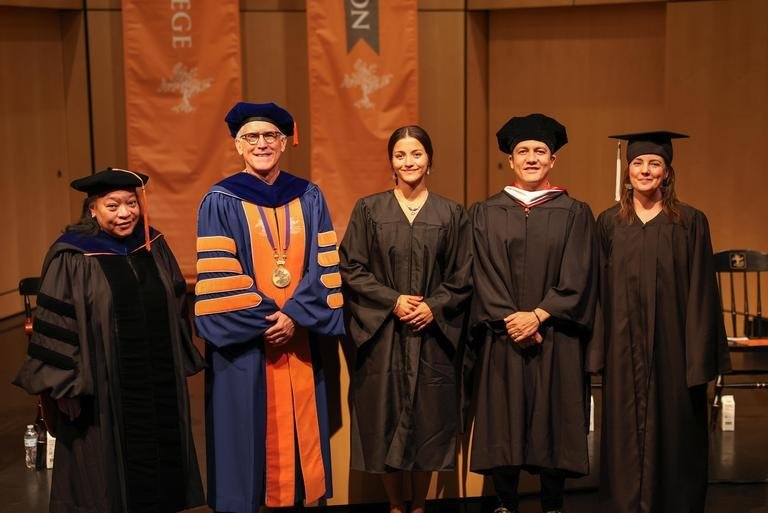 The college president, student senate president and deans standing in front of the podium