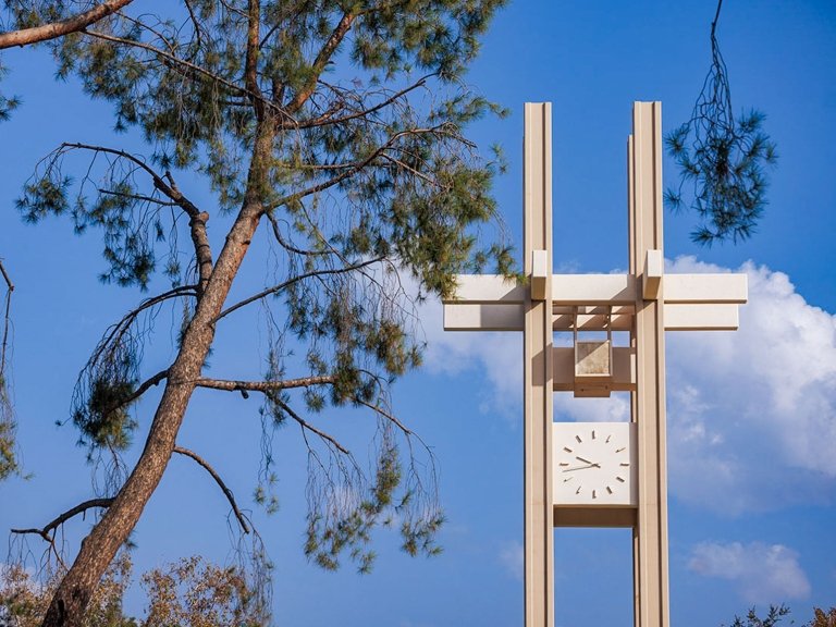 the pitzer clock tower with a pine tree in the foreground