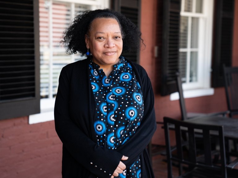 Dean of Faculty Chawne Kimber stands on front porch and wears a black sweater and blue scarf