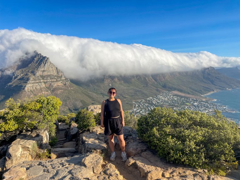 Natasha Yen stands on a hiking trail at Lion’s Head mountain with a backdrop of low-hanging clouds settling over the peaks.