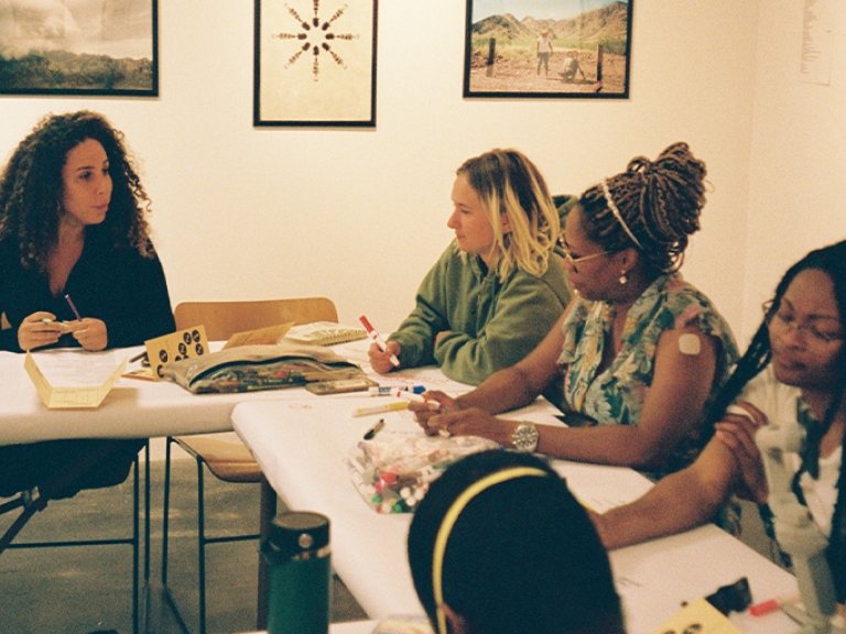 Students and faculty write on white paper covering the tables in Pitzer’s Salathe Gallery.