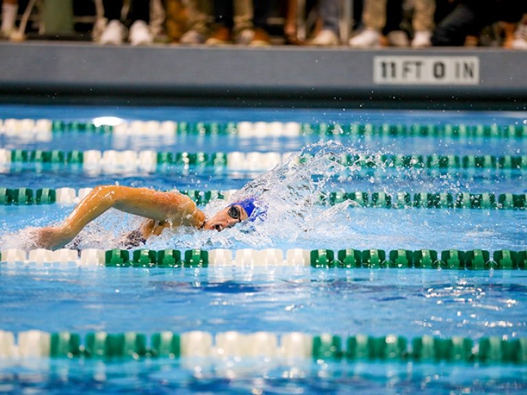 A student on the Pomona-Pitzer women's swimming and diving team swims freestyle during a meet