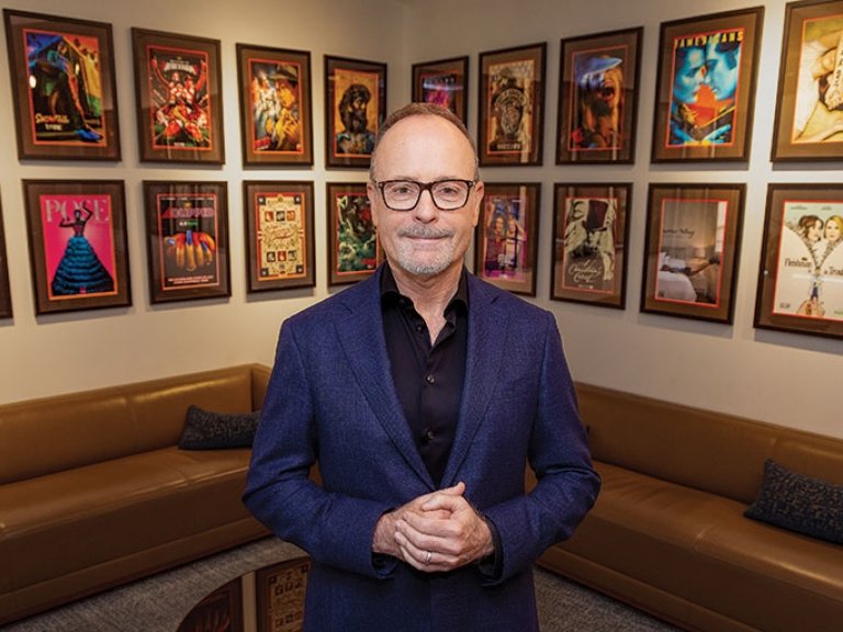 John Landgraff stands in a room decorated with tv posters