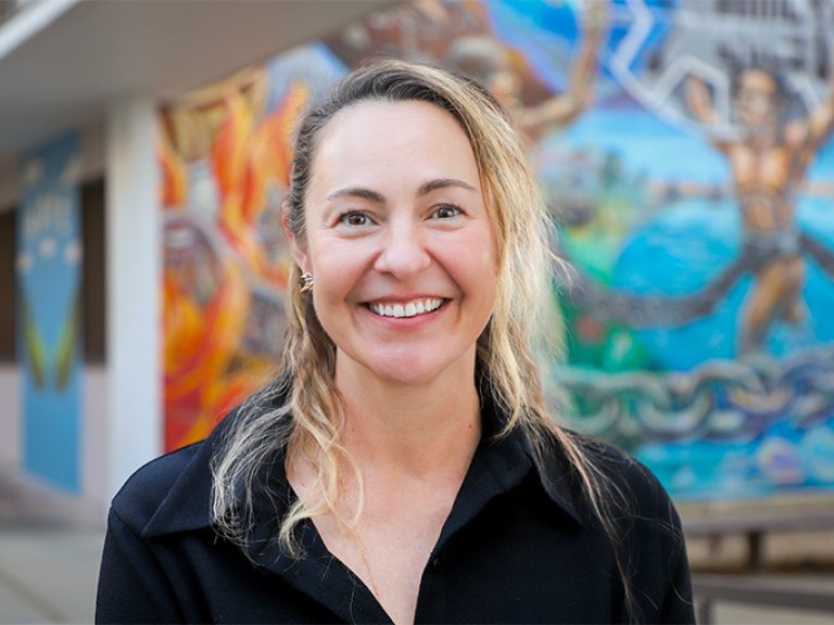 Jessica McCoy stands in front of a mural in the Mead Hall Courtyard