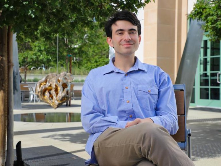 Lucas Oppenheimer sits on a chair in front of the Nucleus