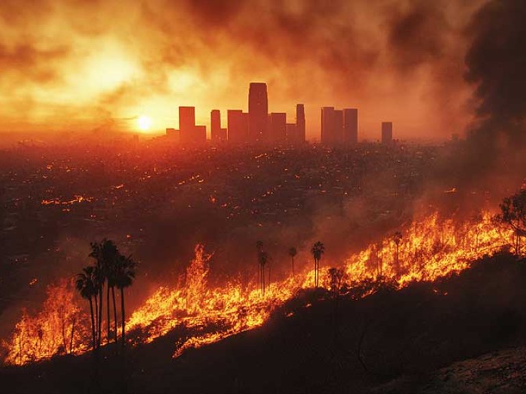 hillside wildfire with the silhouette of downtown Los Angeles in the background