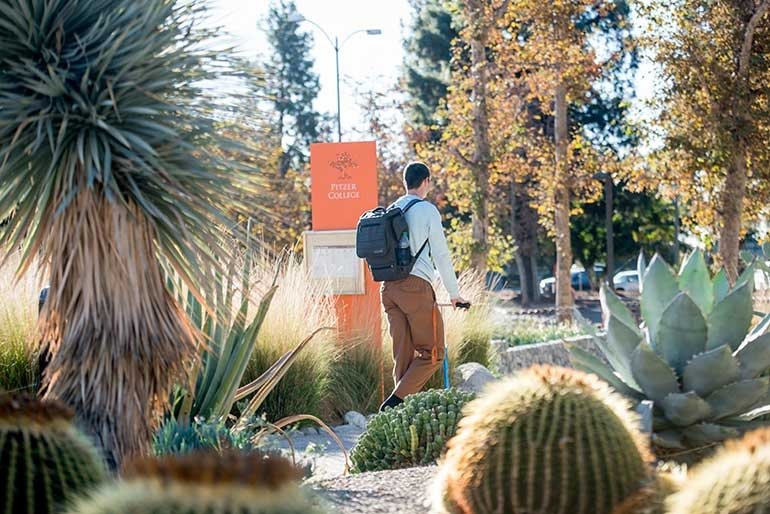 a student scooters through holden garden surrounded by cactus