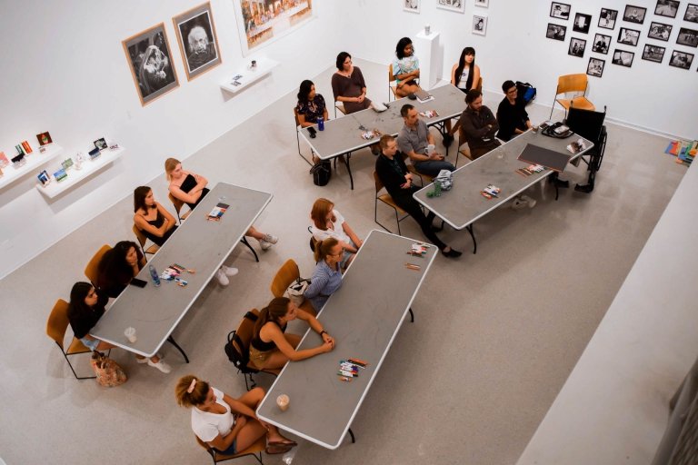 Participants sit at tables in a art gallery workshop 