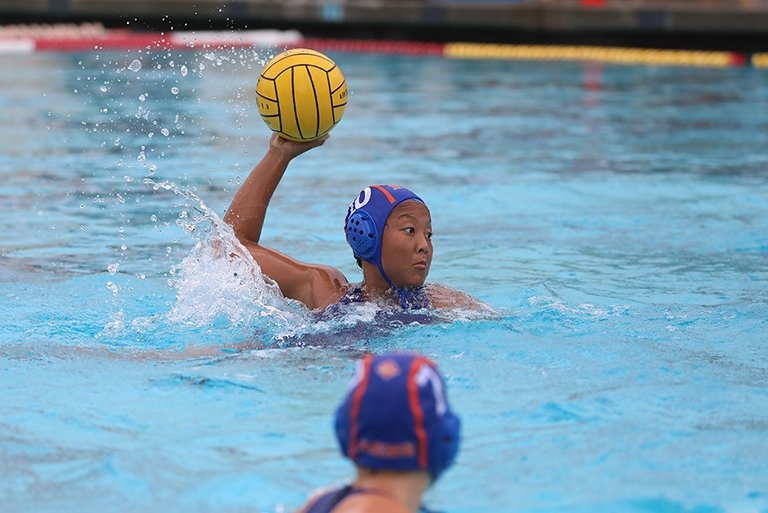 A photo of a female water polo player about to throw the ball.