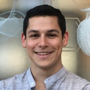 Headshot of Alfredo Freddy Valencia, who has short dark hair and wears a gray shirt.
