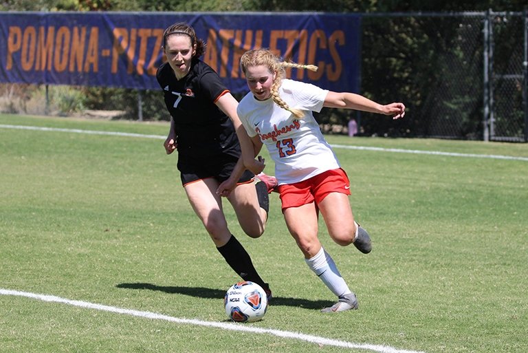 A photo of two female student athletes going after a soccer ball.