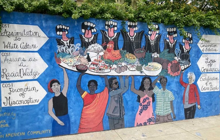 a view of the capas mural showing several people holding up a platter of food