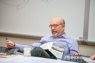 Dan Segal sitting in classroom in purple shirt