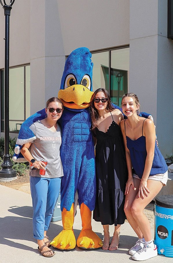 three alumni pose with cecil the sagehen mascot
