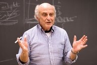 Albert Wachtel in blue stripped shirt speaking in front of classroom