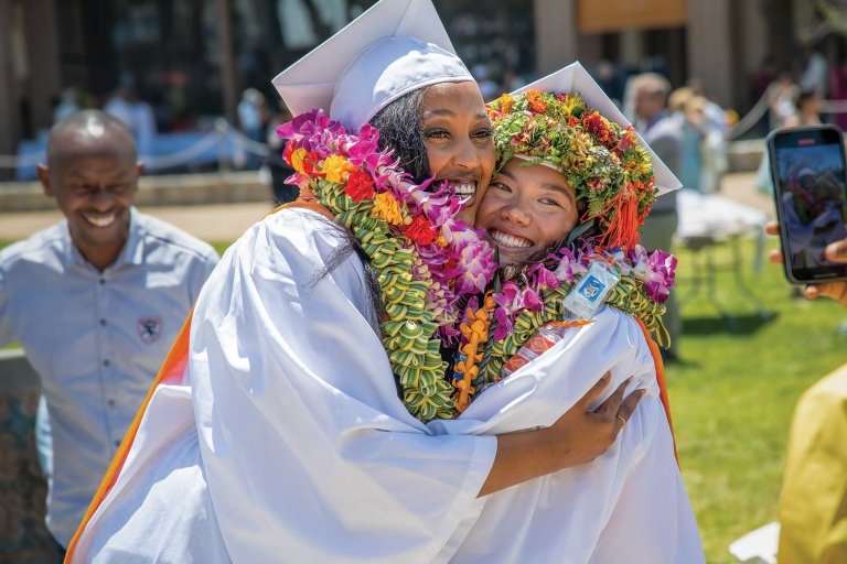 commencement grad hugging and posing for a photo together