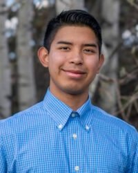 portrait of Jesse Lopez wearing a blue and white checked collared shirt.