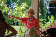 Muriel Poston pointing in front of plants with red shirt