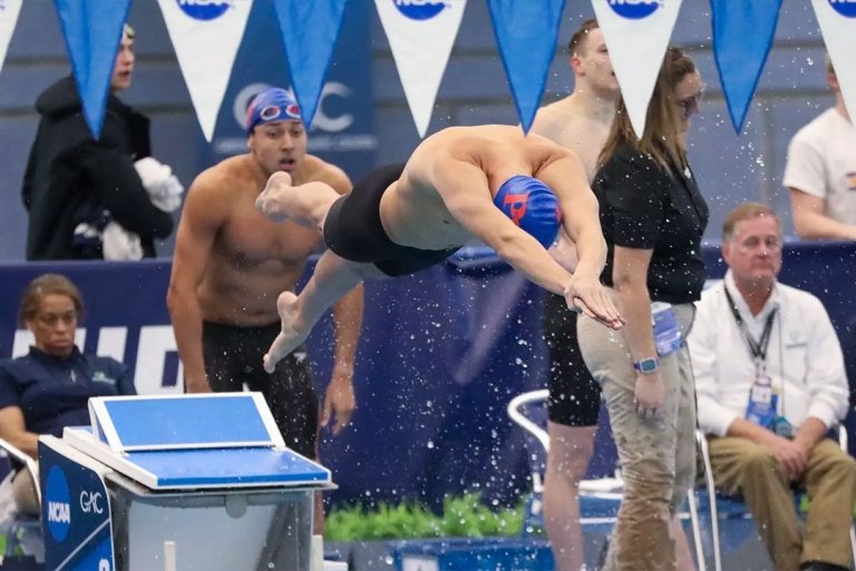 A Pomona-Pitzer men’s swim and dive team member jumps off the diving board.